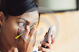 Young beautiful girl applying makeup. Girl coloring eyebrows with eyebrow liner