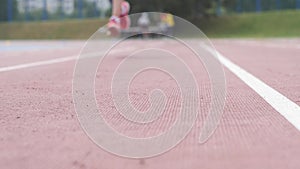 Young beautiful girl athlete training running fast start at the city athletics stadium during a day training in slow