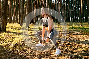 Young and beautiful girl athlete working out with dumbbell outdoors