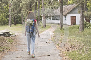 Young beautiful girl with backpack lost at the territory of abandoned summer kids camp