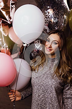 Young beautiful girl with balloons sparkles. At the party, he celebrates his birthday.