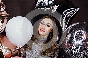 Young beautiful girl with balloons sparkles. At the party, he celebrates his birthday.