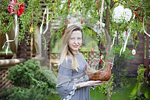 Young beautiful girl with a basket with Easter eggs on background Easter tree