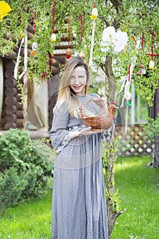 Young beautiful girl with a basket with Easter eggs on background Easter tree