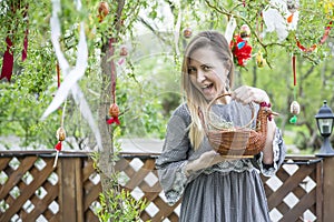 Young beautiful girl with a basket with Easter eggs on background Easter tree