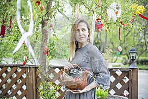 Young beautiful girl with a basket with Easter eggs on background Easter tree