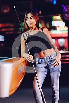 Young beautiful girl in a billiard club, with cue stick posing
