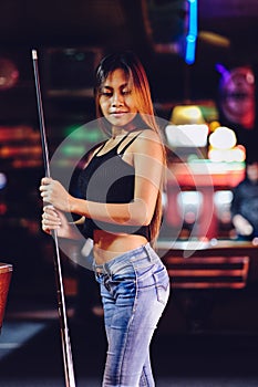 Young beautiful girl in a billiard club, with cue stick posing