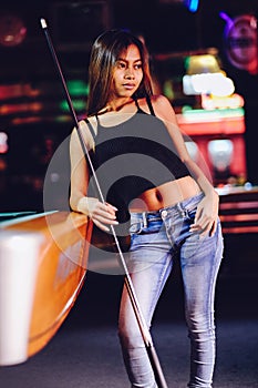 Young beautiful girl in a billiard club, with cue stick posing