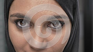 Young beautiful girl in black hijab looking at camera. Portrait, close-up of eyes 60 fps