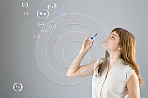 Young beautiful girl blow out soap bubbles