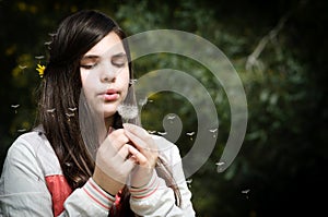 Young beautiful Girl blowing dandelion flower