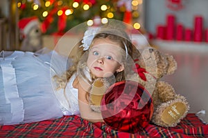 Young beautiful girl in blue white elegant evening dress sitting on floor near christmas tree and presents on a new year