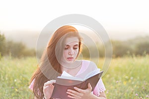 Young beautiful girl with book in the nature