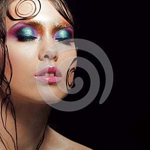 Young beautiful girl bright makeup with a wet look shine, dark background