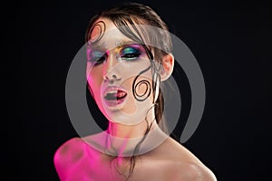 Young beautiful girl bright makeup with a wet look shine, dark background