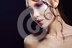 Young beautiful girl bright makeup with a wet look shine, dark background