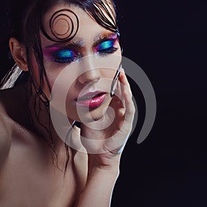 Young beautiful girl bright makeup with a wet look shine, dark background