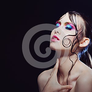 Young beautiful girl bright makeup with a wet look shine, dark background