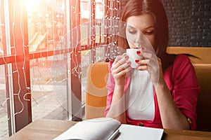 Young beautiful girl, businesswoman drinking tea or coffee sitting in cafe. Business lunch, break