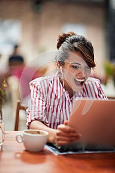 Young beautiful girl at a cafe amazed with laptop content