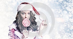 Young beautiful girl with candy on snowy winter background. Christmas and New Year holidays concept.