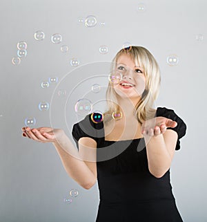 Young beautiful girl catch soap bubbles