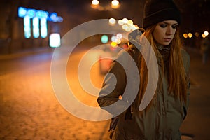 Young beautiful girl catches a taxi in the city street at night