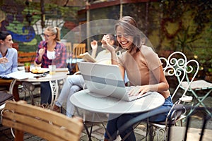 A young beautiful girl is chatting on a laptop while sitting in the bar. Leisure, bar, outdoor