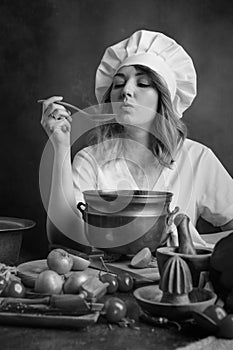 Young beautiful girl in a chef uniform with old pan and wooden