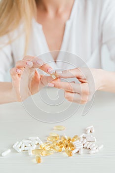 Young beautiful girl chooses pills, colorful capsules of tablets, vitamins, dietary supplements