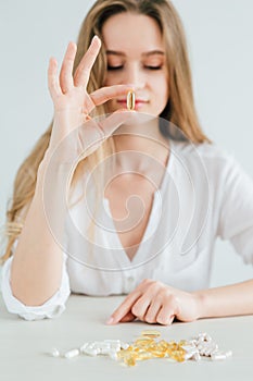 Young beautiful girl chooses pills, colorful capsules of tablets, vitamins, dietary supplements