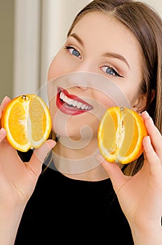 Young beautiful girl closeup portrait with orange fruit, red lipstick and perfect makeup