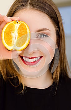 Young beautiful girl closeup portrait with orange fruit, red lipstick and perfect makeup