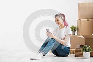 Young beautiful girl with colored hair in a white T-shirt and jeans, talking on the phone and writes messages against