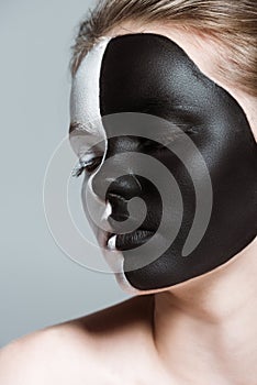 young beautiful girl with creative white and black bodyart on face,