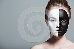 Young beautiful girl with creative white and black bodyart on face looking at camera,