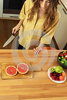 Young beautiful girl is cutting a grapefruit.