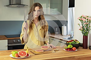 Young beautiful girl is cutting a grapefruit.