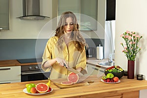 Young beautiful girl is cutting a grapefruit.