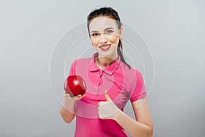 Young beautiful girl with dark curly hair, bare shoulders and neck, holding big red apple to enjoy the taste and