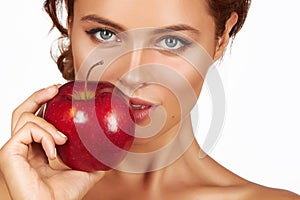 Young beautiful girl with dark curly hair, bare shoulders and neck, holding big red apple to enjoy the taste and are dieting,