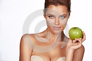 Young beautiful girl with dark hair, bare shoulders and neck, holding big green apple to enjoy the taste and are dieting, hea