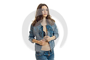Young beautiful girl with dark hair with a denim jacket undone poses on camera