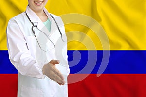 Young beautiful girl doctor with an open smile holds out his hand for greeting on the background of the national flag, concepts of