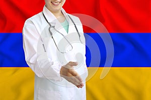 Young beautiful girl doctor with an open smile holds out his hand for greeting on the background of the national flag, concepts of