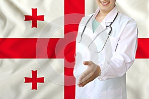 Young beautiful girl doctor with an open smile holds out his hand for greeting on the background of the national flag, concepts of