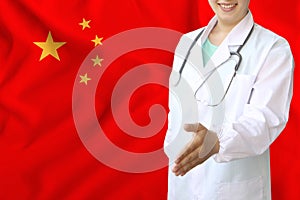 Young beautiful girl doctor with an open smile holds out his hand for greeting on the background of the national flag, concepts of