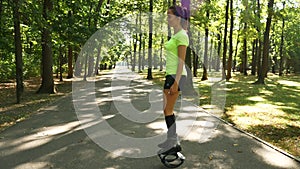 Young beautiful girl doing sports in the park. A woman jumps on special shoes for fitness.