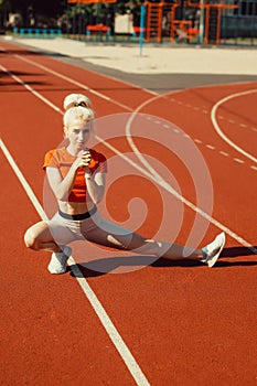 Young beautiful girl doing warm-up before sports exercise at school stadium